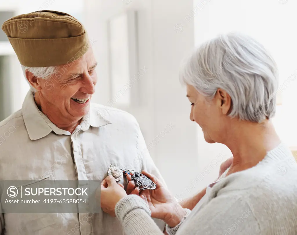 Military veteran, man and woman with medal, uniform and smile together with memory, pride and success. Elderly couple, army badge or regalia with happiness, check and retirement from service in house