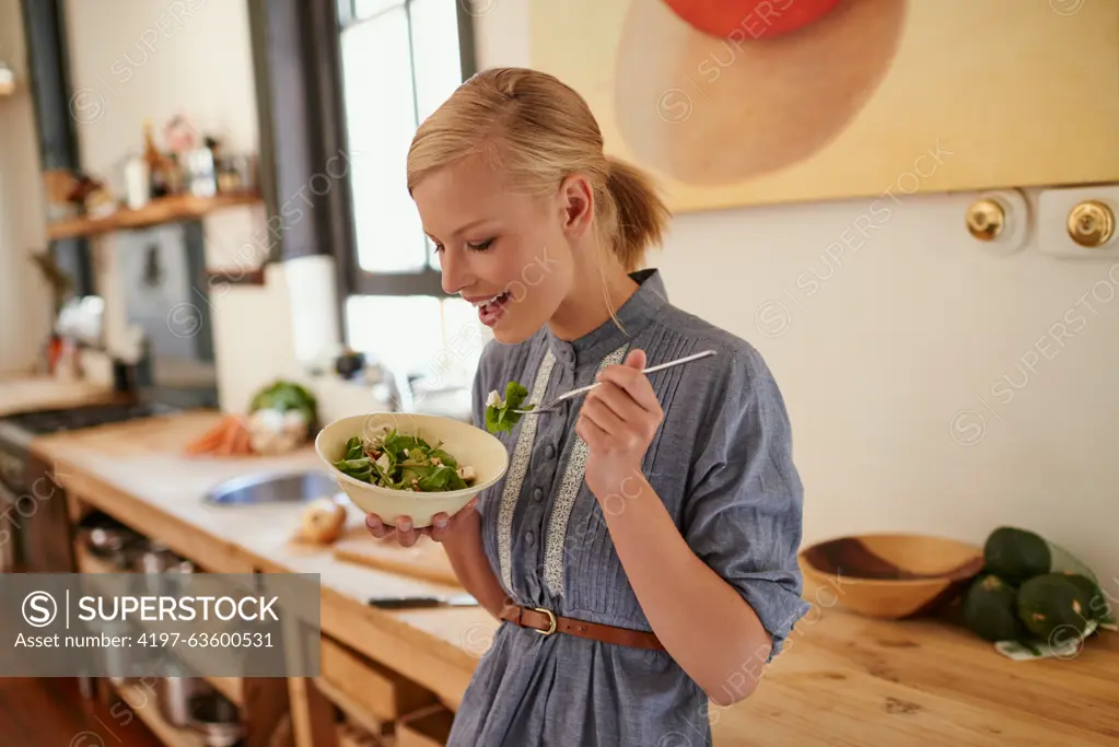 Woman, salad and eating in kitchen for health nutrition for wellbeing, ingredients or fibre. Female person, bowl and vegetable meal in apartment or diet leafy greens or lettuce food, recipe or Canada