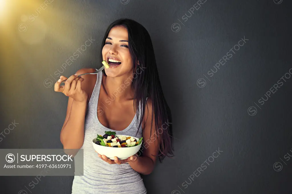 Happy woman is eating a salad, healthy food and nutrition, portrait and vegetables isolated on wall background. Organic, vegan and health with diet, female model to lose weight with mockup space