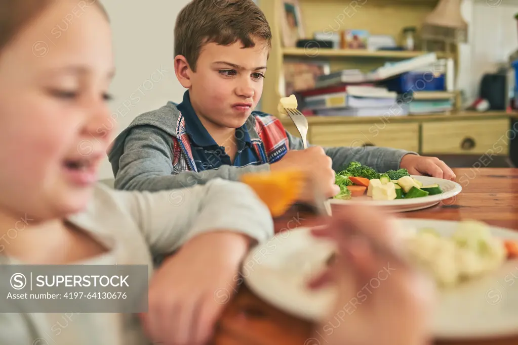 Child, eating and upset with healthy food in home with vegetables, nutrition and angry with diet. Hungry, kid and frustrated with plate of potatoes, salad and dislike for dinner with broccoli