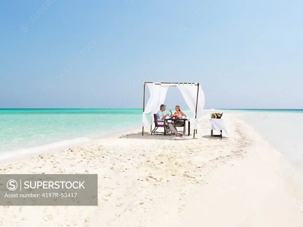 Couple enjoying dinner on the sandy beach resort by the sea