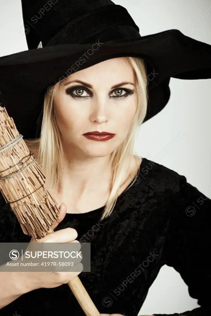 Portrait of a beautiful blonde witch holding her broomstick up on a white background