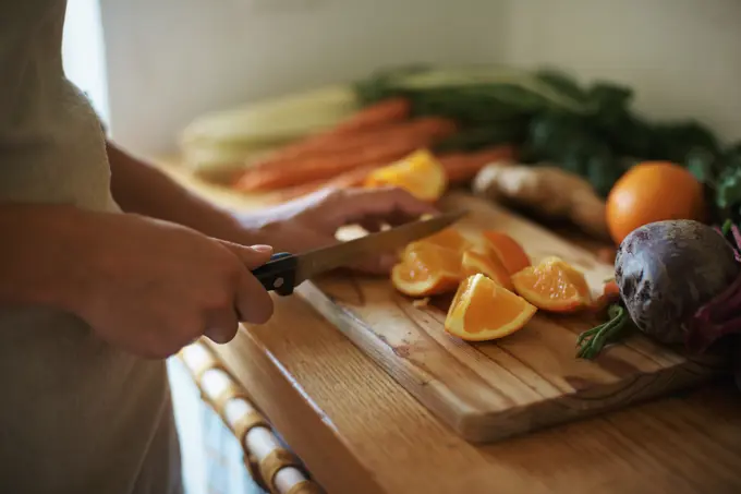 Closeup, kitchen and fruits with woman, vegetables and chopping board with knife and salad. Person, vegan and chef with utensils and ingredients for lunch and supper with healthy meal and diet plan