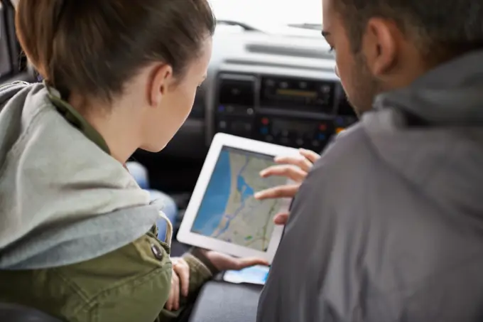 Couple, car and map on road trip with navigation for direction, vacation and travel to destination in countryside. Woman, man and tablet in vehicle for tech or location to holiday journey and tourism