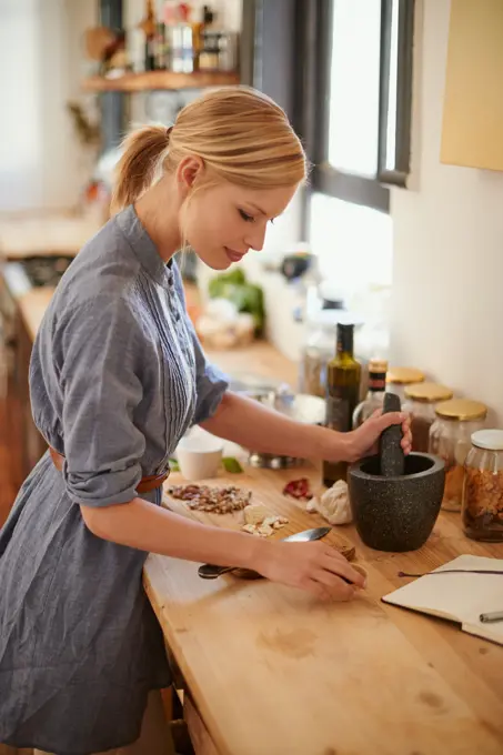 Cooking, woman and mortar with grind in a home with diet, nutrition and healthy food with pestle. Kitchen, bowl and happy from organic and vegan lunch with mushroom and wood board with wellness