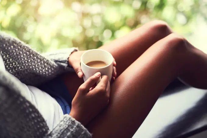 Home, window and hands of person with coffee, cappuccino and mocha latte as hot beverage for breakfast. House, woman and tea cup in morning for relaxing, comfortable and peaceful in apartment