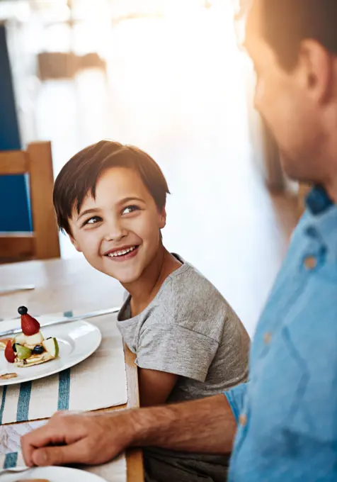 Happy, boy and dad together with breakfast on table for eating, nutrition and sharing with love. Hungry, man and kid in home excited for meal, diet and wellness on social morning with healthy food