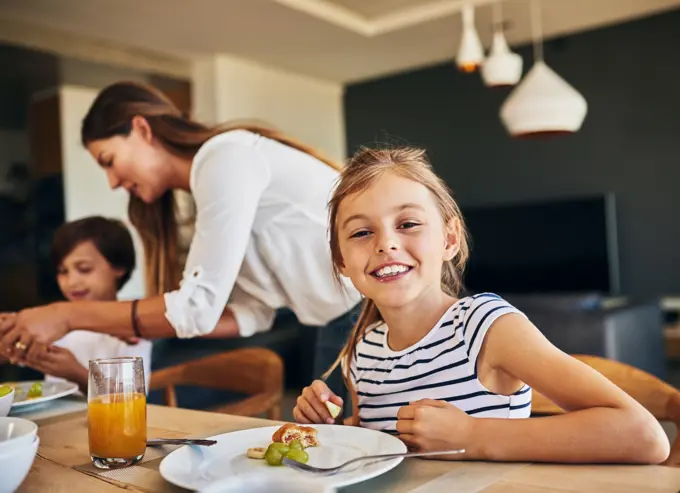 Family, breakfast and portrait of girl at table for diet, nutrition and gut health support. Love, food and face of kid with mother for brunch, meal and wellness with fruit, vitamins or development