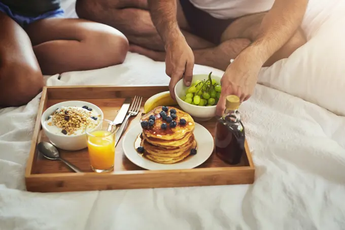 Couple, morning or hands for breakfast in bed for wellness, brunch or food bowl together to relax in home. Valentines day, wake up or people eating for healthy diet, nutrition or orange juice closeup