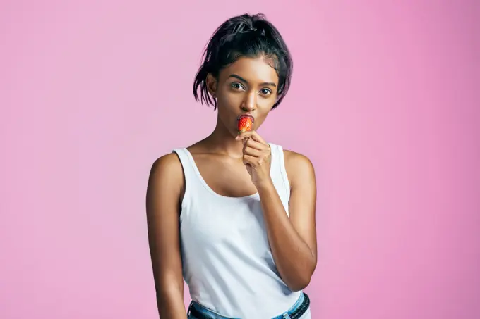 Portrait, strawberry and hands of woman in studio for fruit, nutrition diet or healthy snack on pink background. Food, vitamin c and Indian model for detox, antioxidants or weight loss with mockup