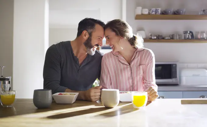 Happy couple, trust or eating breakfast together with love, diet or juice in meal in home kitchen. Romantic people, forehead or morning snack for bonding, support or food in healthy marriage for care