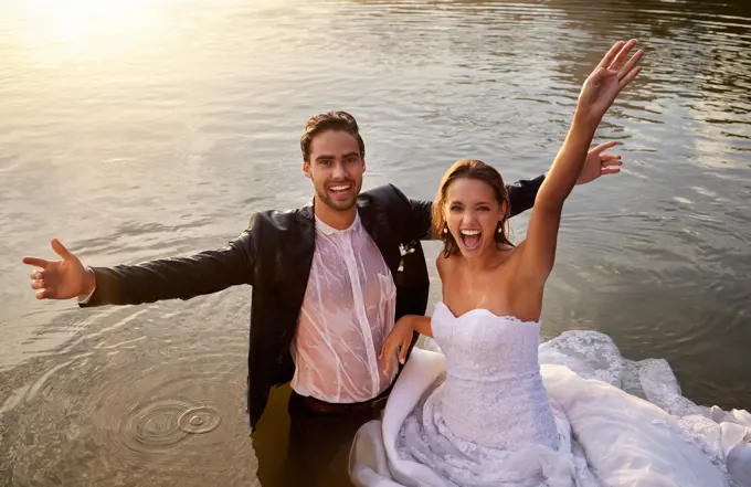 Lake, portrait of wet bride and groom standing in water together with excited smile and playful romance. Love, marriage and happy couple celebrate romantic, loving relationship and wedding in nature.