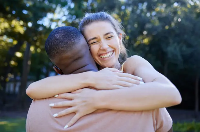 Love, interracial and couple hug, outdoor and smile for bonding, romance and loving together. Romantic, black man and woman embrace in nature, relationship and happiness in park, intimate and dating