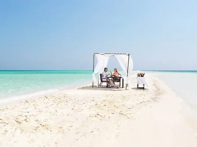 Couple enjoying dinner on the sandy beach resort by the sea