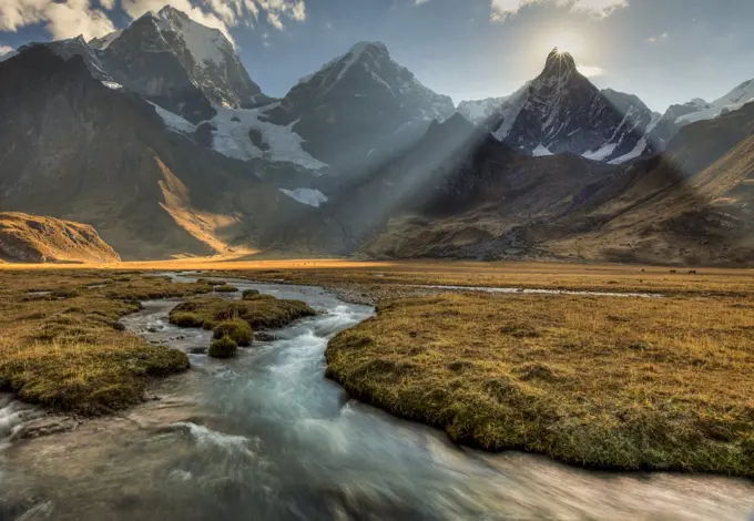 Sun sets behind Jirishanca peak with Yerupaja peak and river flowing into Carhuacocha Lake, Cordillera Huayhuash, Andes, Peru