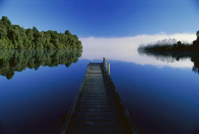 Wood dock reaching out into Lake Mapourika, West Coast, South Island, New Zealand