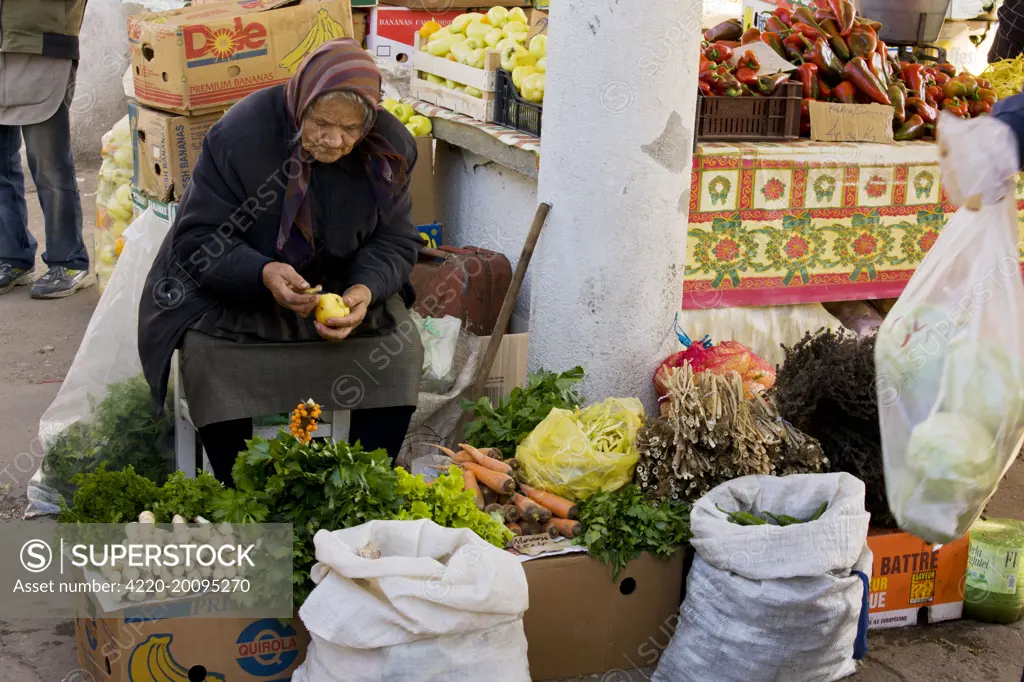 Stall-holder with vegetables and herbs at Sigishoara fruit and vegetable market. Transylvania, Romania.