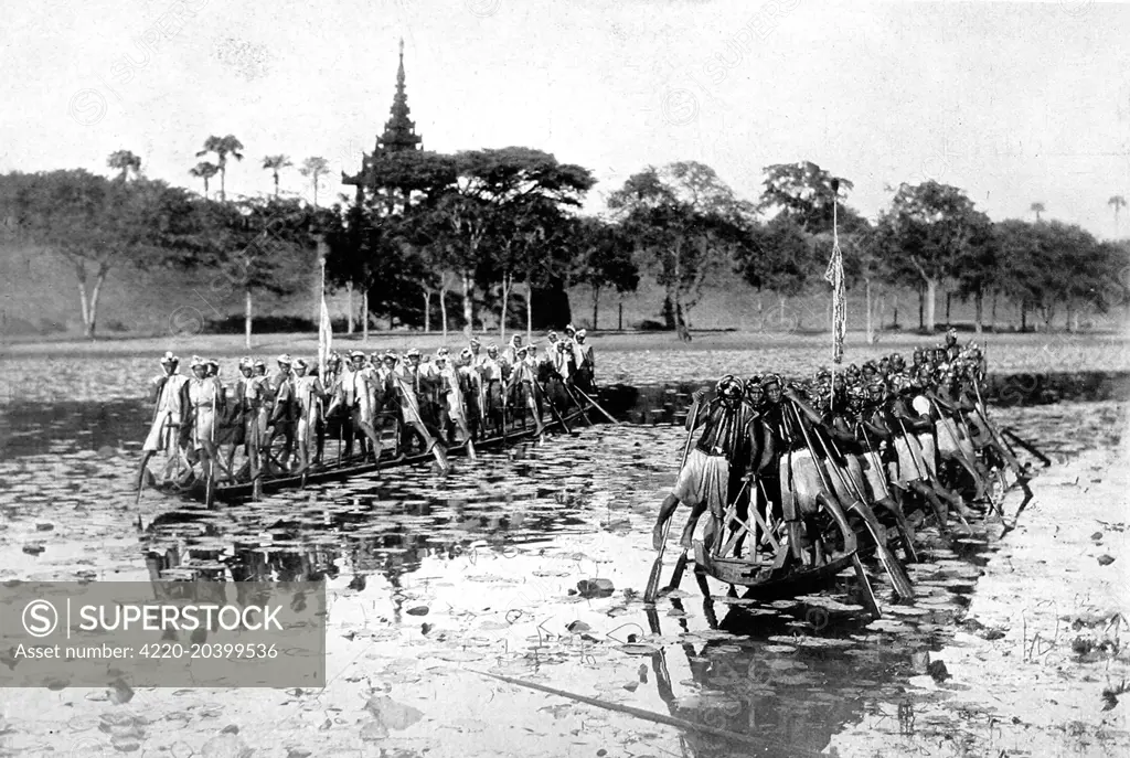 Photograph of two Burmese canoes, each with at least twenty rowers, 1910.  Each rower balanced on the inside foot, with the outside one slipped through a strap on the oar; thus they used an arm and a leg to work each oar.     Date: 1910