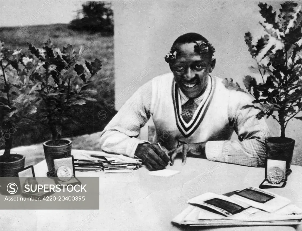 Photograph of Jesse James Cleveland Owens, the US athlete, pictured with his Olympic oak-trees and medals, 1936.    Owens won four gold medals at the the 1936 Berlin Olympics - the 100 metres, the 200 metres, the long jump and the 4x100 metres relay.     Date: 1936