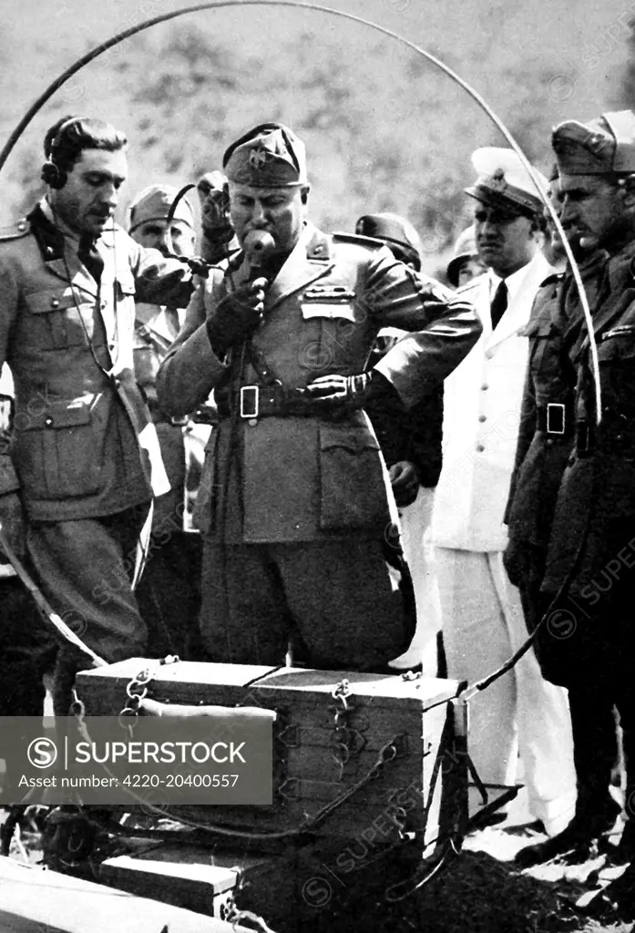 Photograph showing Benito Mussolini (1883-1945), the Italian dictator, testing a radio set during the Italian Army manoevres of August 1936.      On 30th August that year Mussolini broadcast a speech in which he claimed that the Italian army could mobilise 8 million men, with only a few hours notice.     Date: 1936