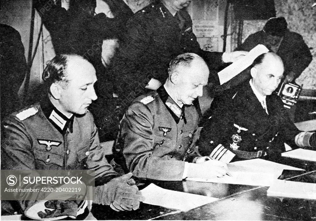 Photograph showing General Gustav Jodl (centre), the Nazi Chief-of-Staff,  signing the unconditional surrender of Germany, bringing an end to the Second World War in Europe.  This surrender took place at the Supreme Headquarters Allied Expeditionary Force at Rheims in France on 7th May 1945.     Date: 1945