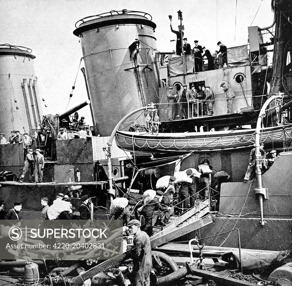 Photograph showing the seamen of HMS 'Coventry' carrying sacks of potatoes onto their ship, as it is refitted at a British dockyard in 1940.    HMS 'Coventry' was an anti-aircraft cruiser of 4290 tons.     Date: 20/07/1940