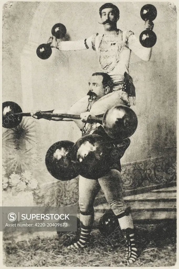 A Turkish wrestler, Ryza Bey, lifts enormous dumbells whilst another strongman colleague sits on his shoulders. A series of cards (2 of 4) depicting a Turkish wrestler, juggler, weightlifter, strongman and entertainer. Yagli gures (Turkish wrestling) is the Turkish national sport. It is commonly known as oil wrestling (sometimes as grease wrestling) because the wrestlers douse themselves with olive oil. It is related to Uzbek Kurash, Tuvan Khuresh and to Tatar Koras. The wrestlers, known as pehl