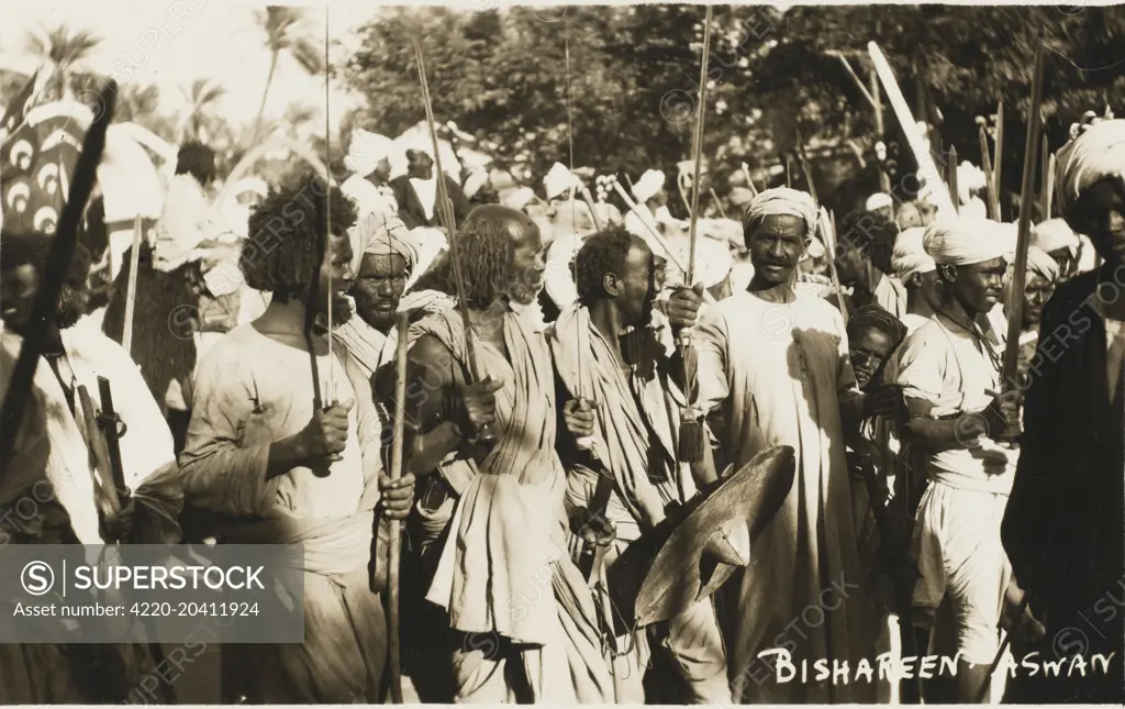 The Bisharin are a Sunni Muslim tribe of the Beja nomadic ethnic group in the eastern part of the Nubian Desert in Sudan - close to Aswan. Here they are taking part in a festival, bearing swords, spears and shields     Date: 1910s