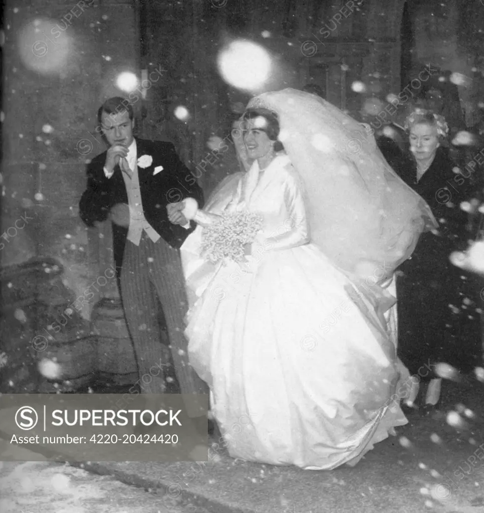 Lady Pamela Mountbatten (born 1929), younger daughter of Lord Louis Mountbatten, emerging with her groom, David Hicks (1929 - 1998) from Romsey Abbey during a snowstorm on their wedding day, 13th January 1960.     Date: 1960