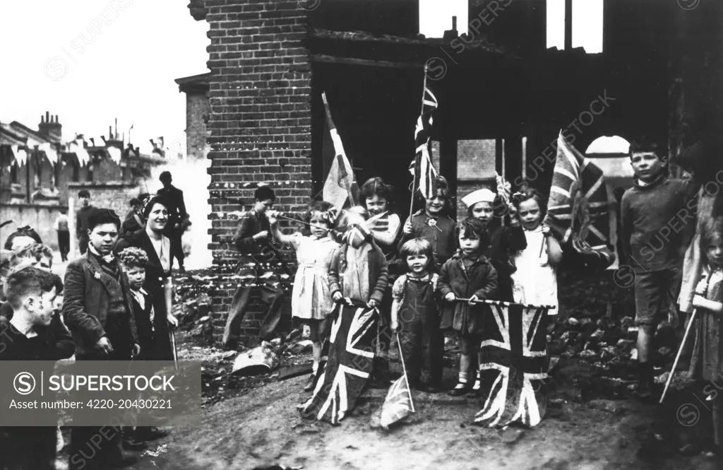 Children celebrate victory day in Europe by waving the union flag in a bombed out house in South London, May 8th 1945  1945