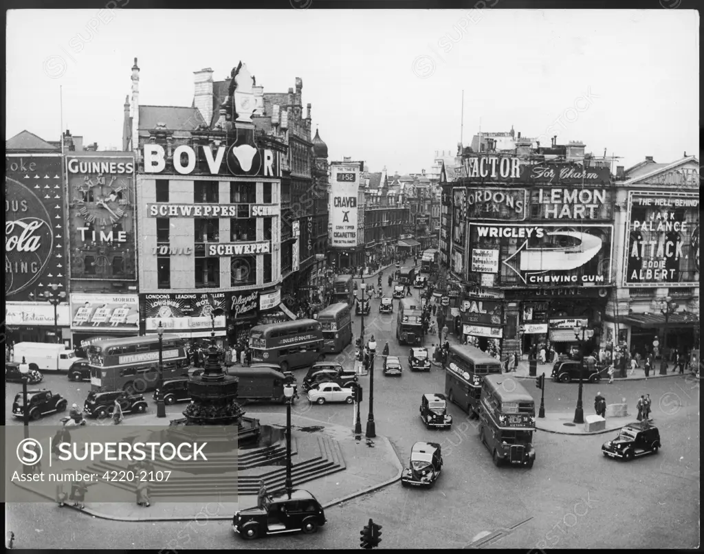 Piccadilly Circus streetscene, with huge billboards advertising Bovril, Wrigley's and Craven A cigarettes amongst othersDate: 1956