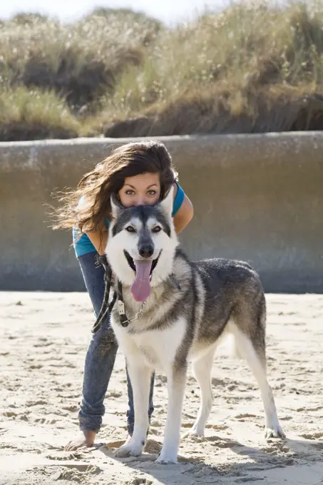 Teenage Girl with Alaskan Malumute (cross) dog on beach . Norfolk UK.