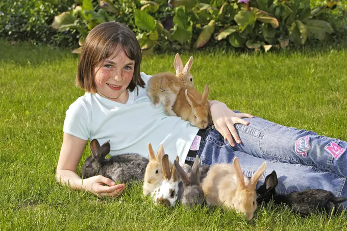 Girl - lying in garden surrounded by rabbits 