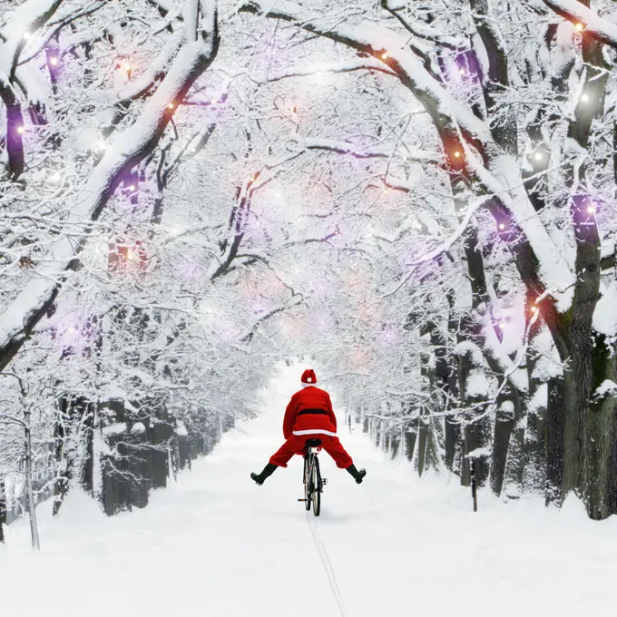 Father Christmas riding through avenue in winter snow with Christmas lights. 