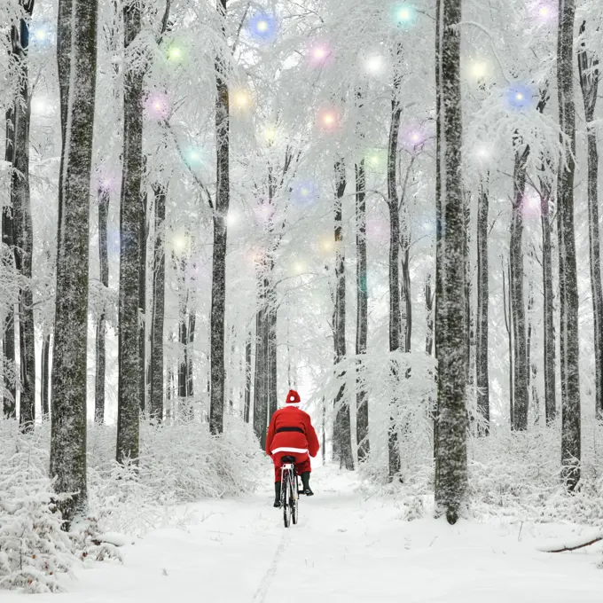 Father Christmas riding through woodland covered in winter snow with Christmas lights 