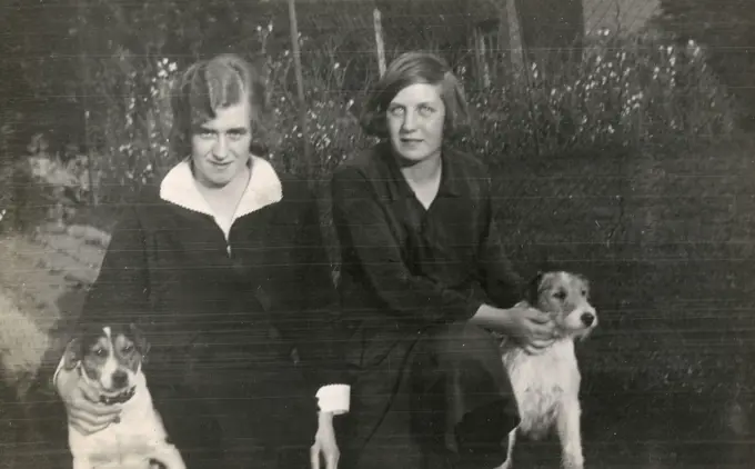 Two women and two terriers in a garden.      Date: circa 1930s