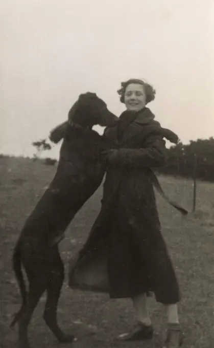 Woman with large dog in a field.      Date: circa 1930s