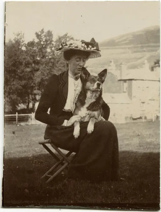 Woman with dog in a garden.      Date: circa 1900s