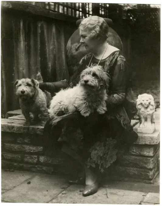 Woman in a garden with two dogs.      Date: circa 1930s