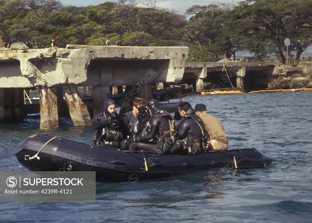 Two pairs of SEAL Team THREE (ST-3) combat swimmers sitting in a combat rubber raiding craft (CRRC) dawn their face mask and prepare to go on bag for two minutes to breath out all the nitrogen in their closed circuit LAR-V oxygen rebreathers prior to commencing the combat swim navigating around Ford Island in the turbid but warm ocean waters of Pearl Harbor on Oahu, Hawaii.