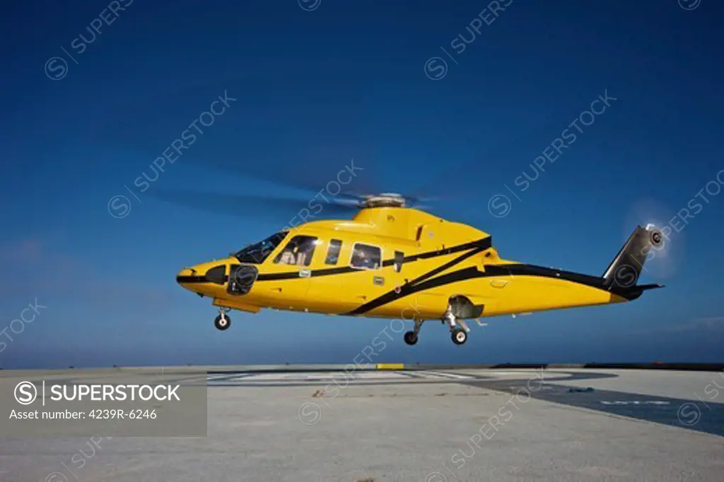 A Sikorsky S-76 utility helicopter taking off from an oil rig.