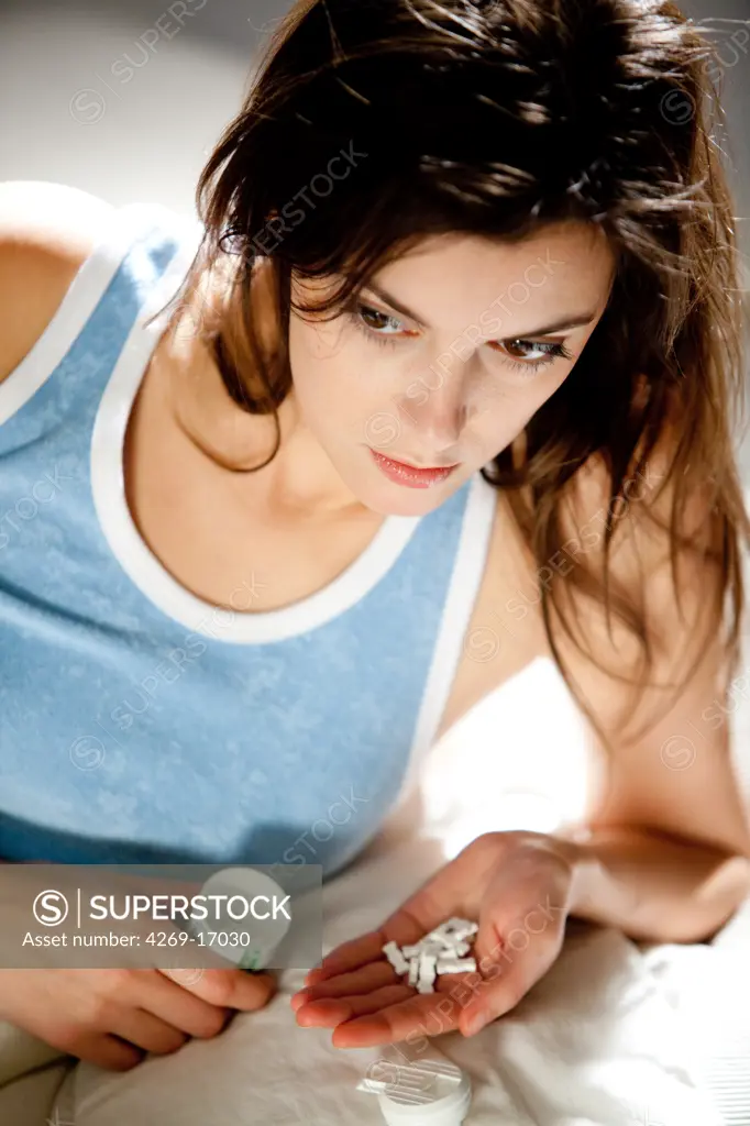 Woman taking tranquilizer pills (anxiolytic).