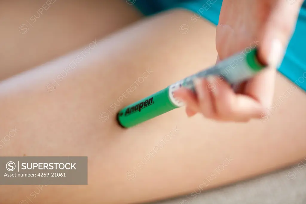 Woman giving herself injection of epinephrine (adrenaline) in her thigh, an emergency treatment in case of anaphylactic or anaphylactoid shock (allergies to drugs, food or insects bites).