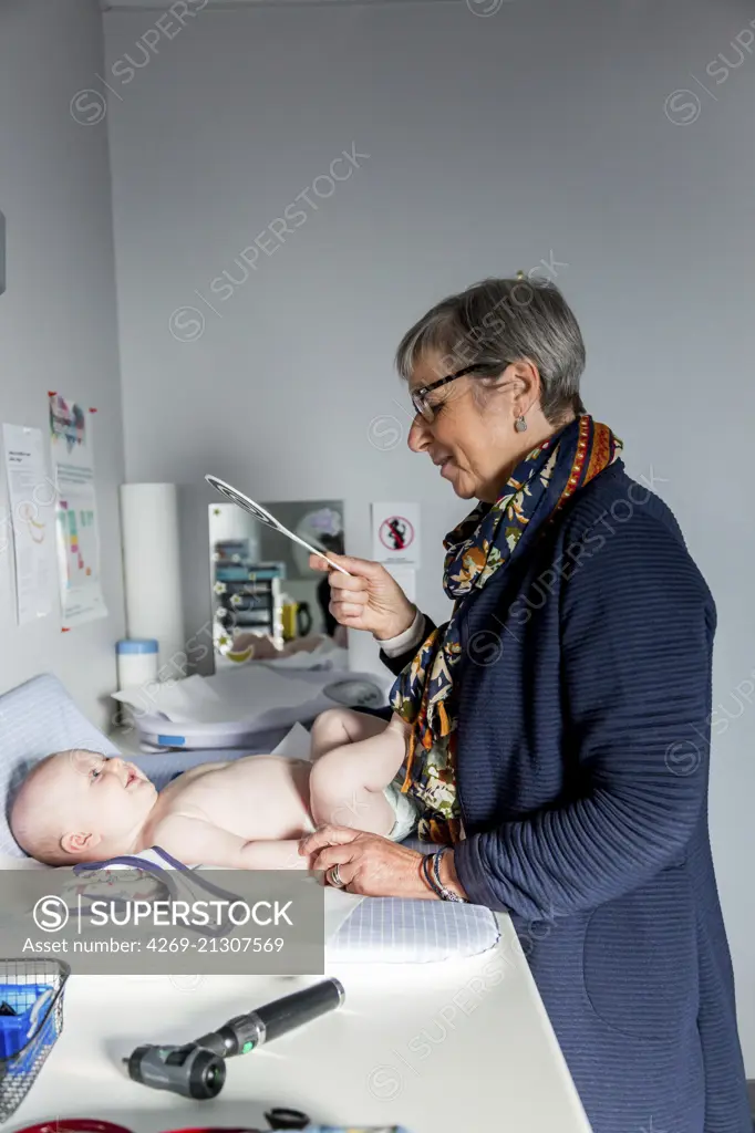 General practitioner with baby, Geveze, France.