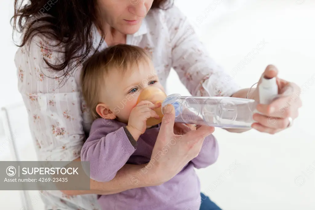 Mother giving her 13 month old baby girl bronchodilatator with a spacer (inhalation chamber) for asthma treatment.