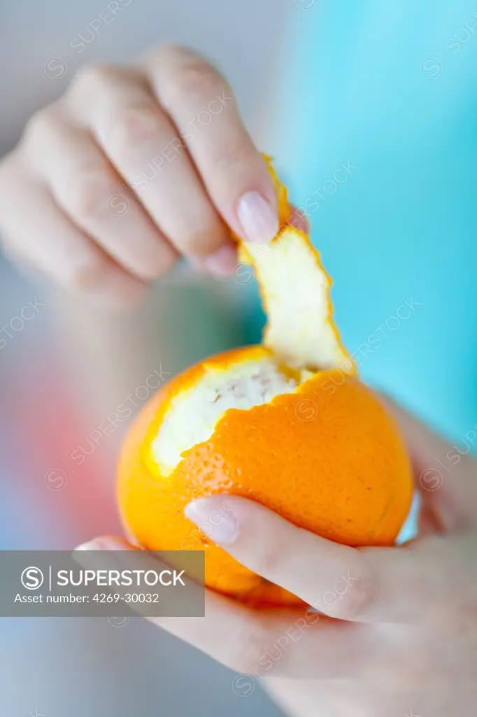 Woman peeling  an orange.