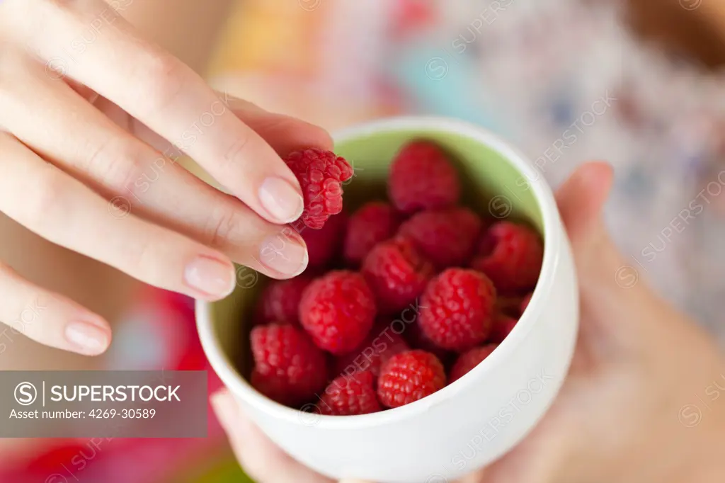 Food. Woman eating raspberries.