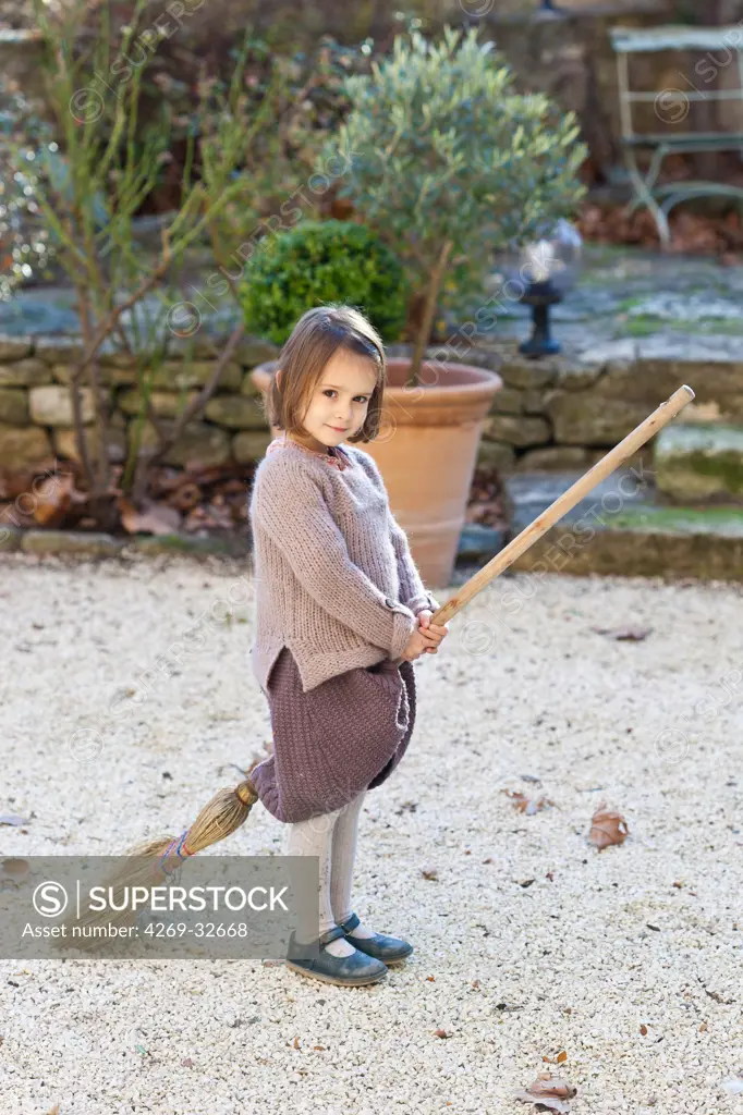 4 year old girl playing the witch on a broom.