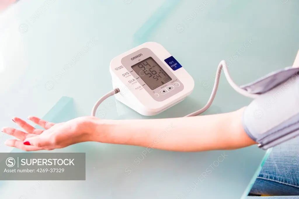 Woman taking her blood pressure with a portable blood pressure monitor.