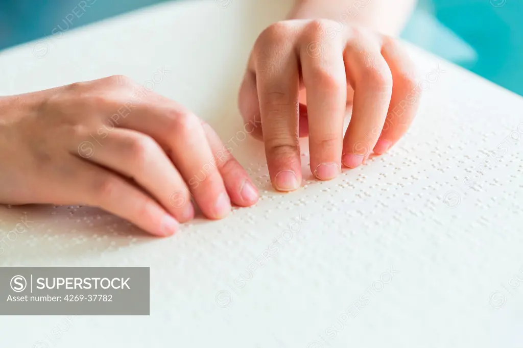 Hands of a blind child reading braille.